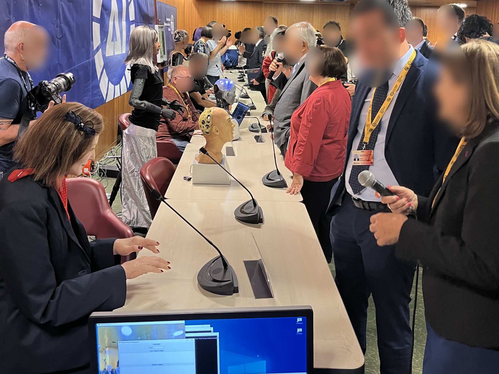 Press and delegates around a row of robots, with Nadine in the foreground, at ITU